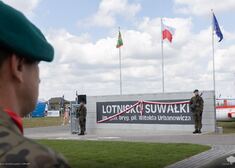 Żołnierze stoją obok tablicy z nazwą lotniska.