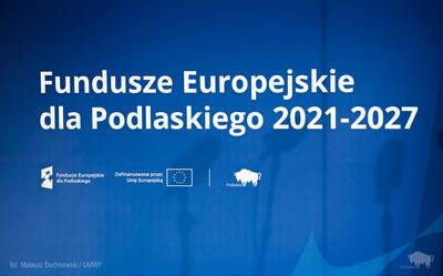 Niebieska plansza z napisem "Fundusze Europejskie dla Podlaskiego 2021-2027"