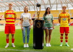 Cztery młode osoby stoja w koszułkach piłkarskich oraz w koszulkach z napisami reklamowymi.