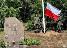 Kamienny głaz z napisem oraz flaga wciągana przez żołnierzy na maszt