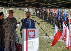 Bogdan Dyjuk, członek zarządu przemawia z mównicy, na której widnieje godło Polski