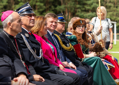 Osoby duchowne, mundurowi, cywile oraz rekonstruktorzy siedzą w rzędzie