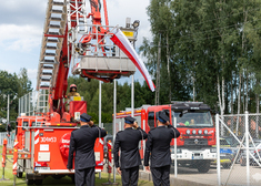 Strażacy salutują przez wciąganym sztandarem na dźwigu