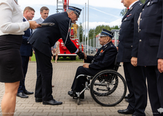 Komendant gratuluje starszemu strażakowi w towarzystwie wicemarszałka Marka Malinowskiego