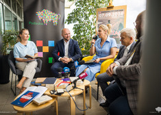 Piątka uczestników konferencji siedzi przy stole i przemawia do mikrofonów.