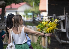 Kobiety trzymają kwiaty w wyciągniętej ręce.