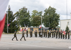 Dwóch oficerów podchodzą do żołnierzy stojących w szeregu.