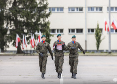 Trzech żołnierzy maszeruje w stronę kamery.