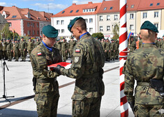 Żołnierze przekazują sobie flagę.