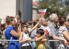 Dziecko będące na widowni uroczystości, macha flagą polski.