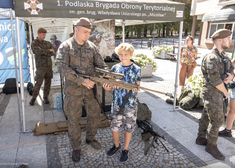 Żołnierz pokazuje dziecku karabin.