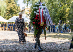 Żołnierz z wieńcem i Wiesława Burnos podchodzi do pomnika.