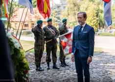 Ambasador Niemiec stoi na baczność przy wieńcu.