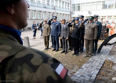 Przedstawiciele służb mundurowych salutują przed pomnikiem synagogi.