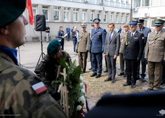 Wojewoda i przedstawiciele służb stoją przed wieńcem.