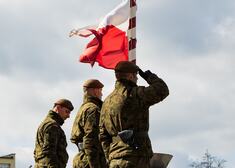 żołnierze stojący na baczność przy polskiej fladze