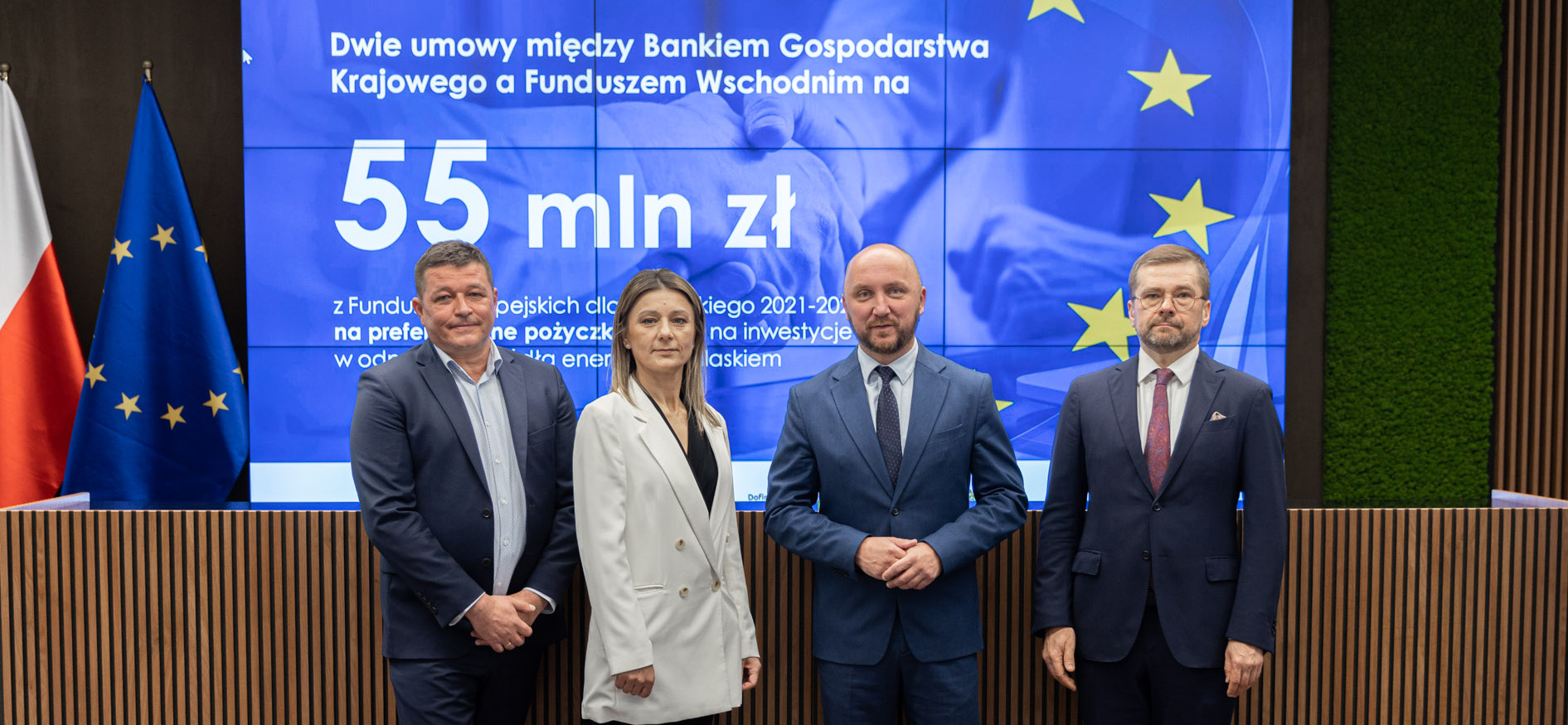 Czterech uczestników konferencji na tle planszy z kwotą na pożyczki.