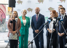 Uczestnicy konferencji na tle ścianki. Przemawia rzecznik marszałka.