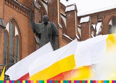 Pomnik Jana Pawła II. W tle Archikatedra Białostocka. Na pierwszym planie flagi biało-żółte