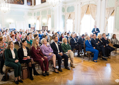 Publiczność siedzi na krzesłach.