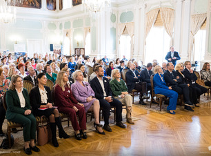 Publiczność siedzi na krzesłach.