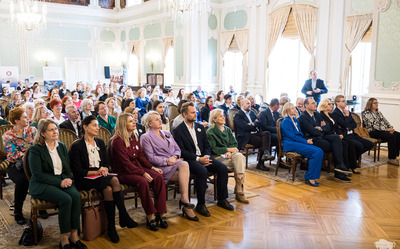 Publiczność siedzi na krzesłach.