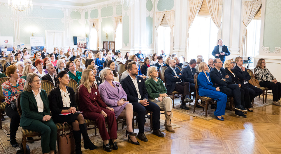 Publiczność siedzi na krzesłach.