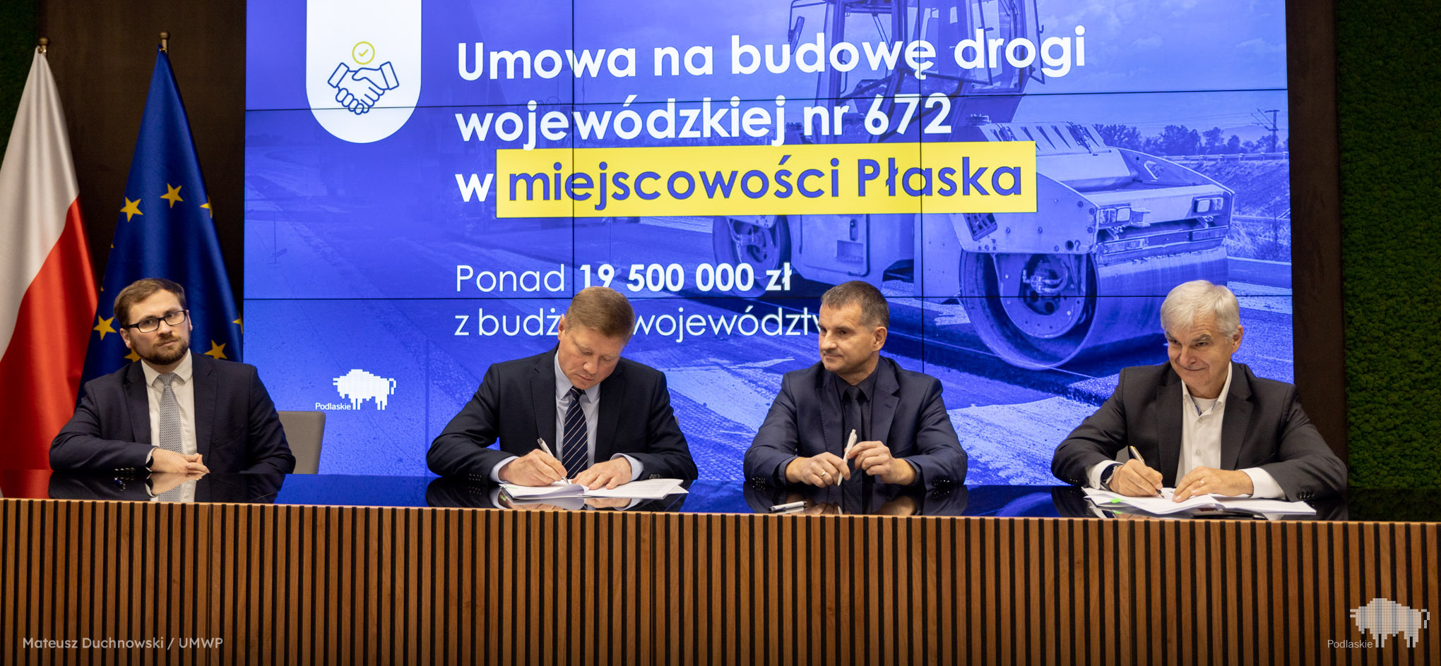 Mężczyźni przy stole podpisują dokumenty