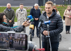 Kolejny mężczyzna przemawia, kilkanaście słucha, w tle widok bloków mieszkaniowych