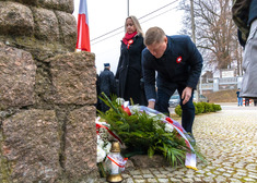 Mężczyzna układa wstęgę na wieńcu przed pomnikiem