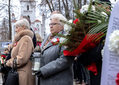 Kobiety przed nimi wiązanka z biało-czerwonych kwiatów