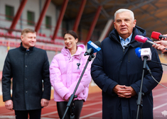 Mężczyzna mówi do mikofonu, w tle bieżnia stadionowa