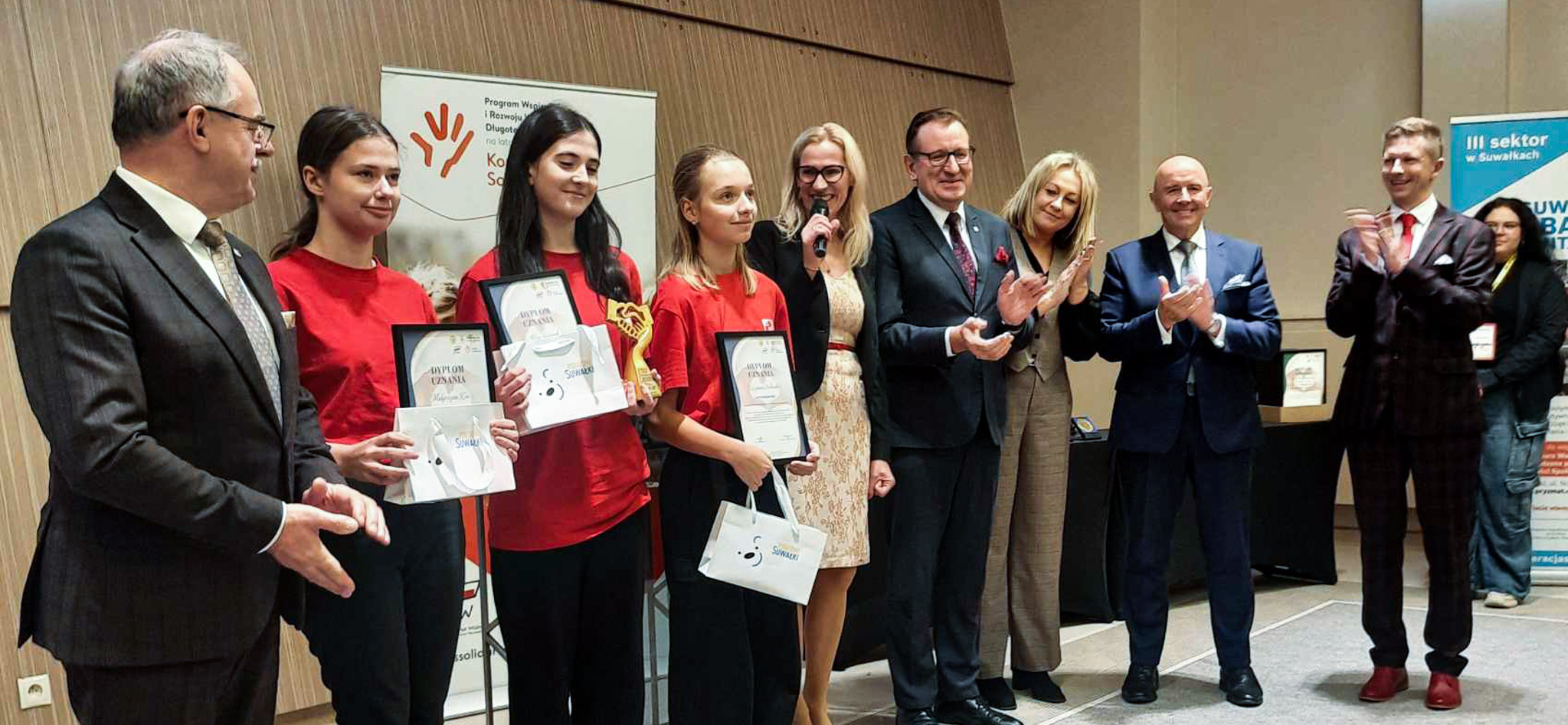 Kilkanaście osób stoi na scenie, część z nich to laureaci konkursu dla wolontariuszy.