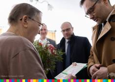 Wiceminister wręcza kobiecie kartkę świąteczną.22] Odwiedziny kombatantów w Augustowie-12.jpg