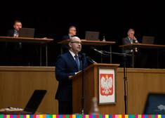 Marszałek Kosicki zabiera głos za mównica z godłem Polski