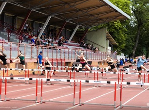 Zawodniczki biegną przez płotki na stadionie lekkoatletycznym.