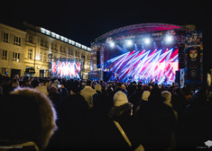 Widok dużej ilości uczestników koncertu z okazji białostockiego finału Wielkiej Orkiestry Świątecznej Pomocy z kolorowa oświetloną sceną