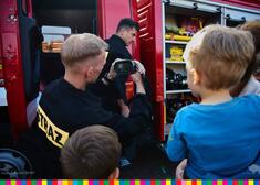 Strażak pokazuje dzieciom wyposażenie wozu