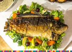 Ryba ułożona na talerzu, ozdobiona sałatą i owocami.