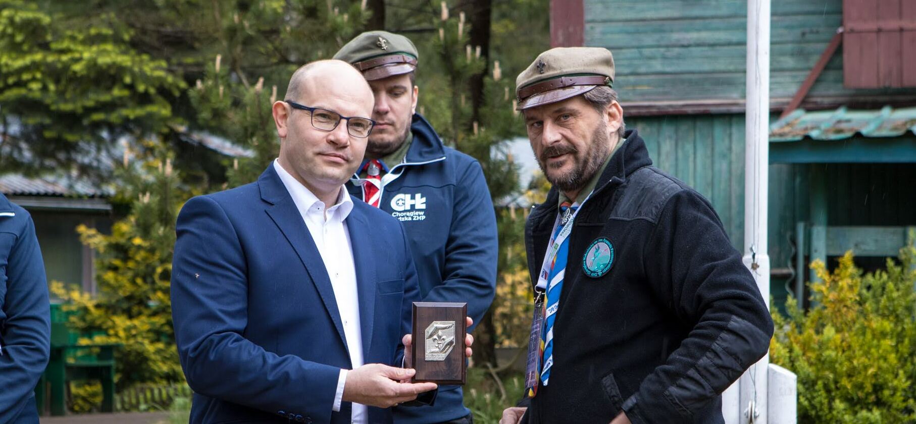 Marszałek z odznaczeniem, obok stoi stoi dwóch druhów