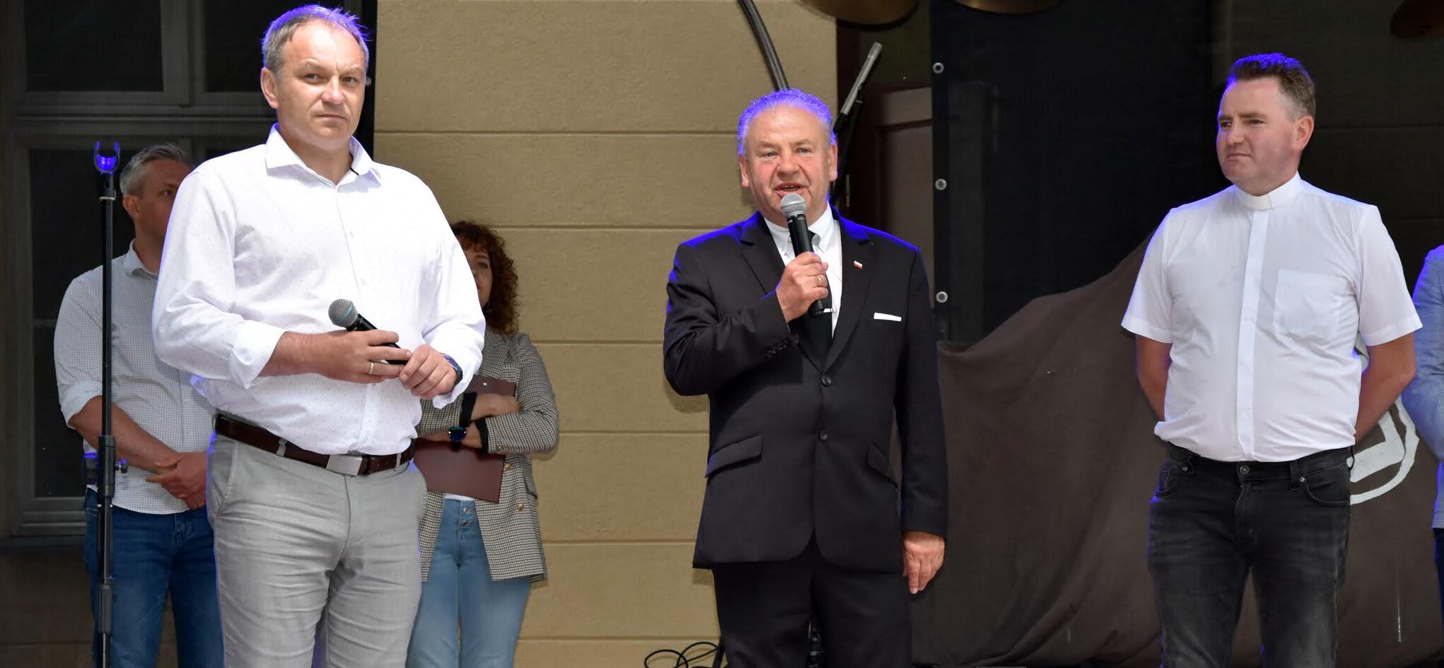 Pomiędzy dwoma mężczyznami stoi wicemarszałek Olbryś, trzyma on mikrofon przy ustach