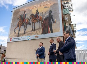 Czterech mężczyzn po prawej stronie. Po lewej budynek z muralem.