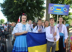 grupa mlodych osób pozuje do zdjęcia trzymając flagę Ukrainy