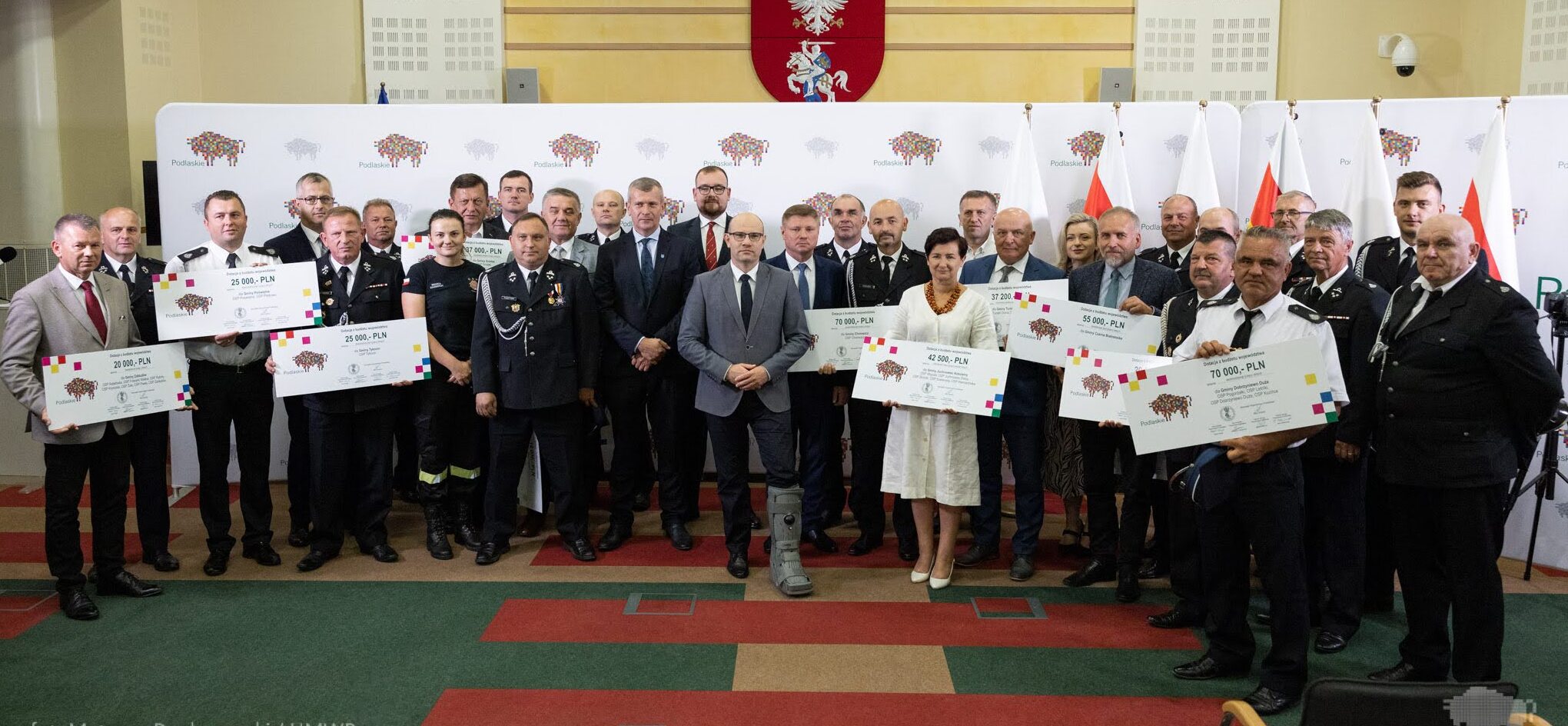 grupa osób uczestnicząca w wydarzeniu pozuje do wspólnego zdjęcia trzymając czeki