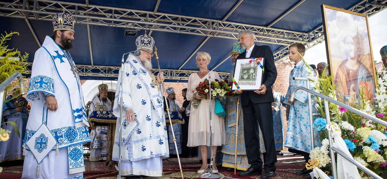 Wiesława Burnos i Sławomir Nazaruk przekazują kwiaty i makatkę zwierzchnikowi Cerkwi