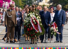 Mundurowi i mężczyźni w garniturach podczas składania wieńców pod pomnikiem 