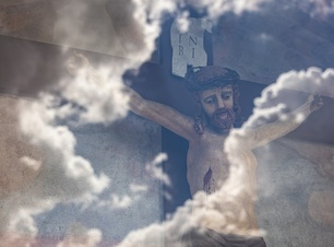 Krucyfiks. W szybie, za którą się znajduje Pan Jezus na krzyżu, odbija się niebo oraz chmury