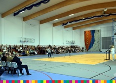Uczestnicy wydarzenia zebrani na trybunach sali gimnastycznej