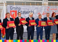 Kilkanaście osób trzyma grawertony