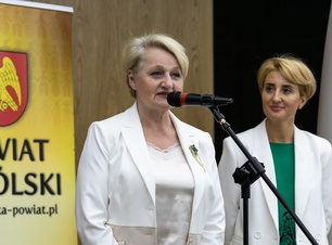 Kobieta ubrana na biało przemawia do mikrofonu